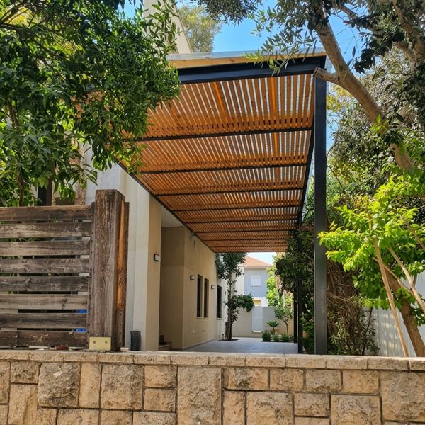 פרגולת עץ מעל מעבר צדדי בכניסה לבית